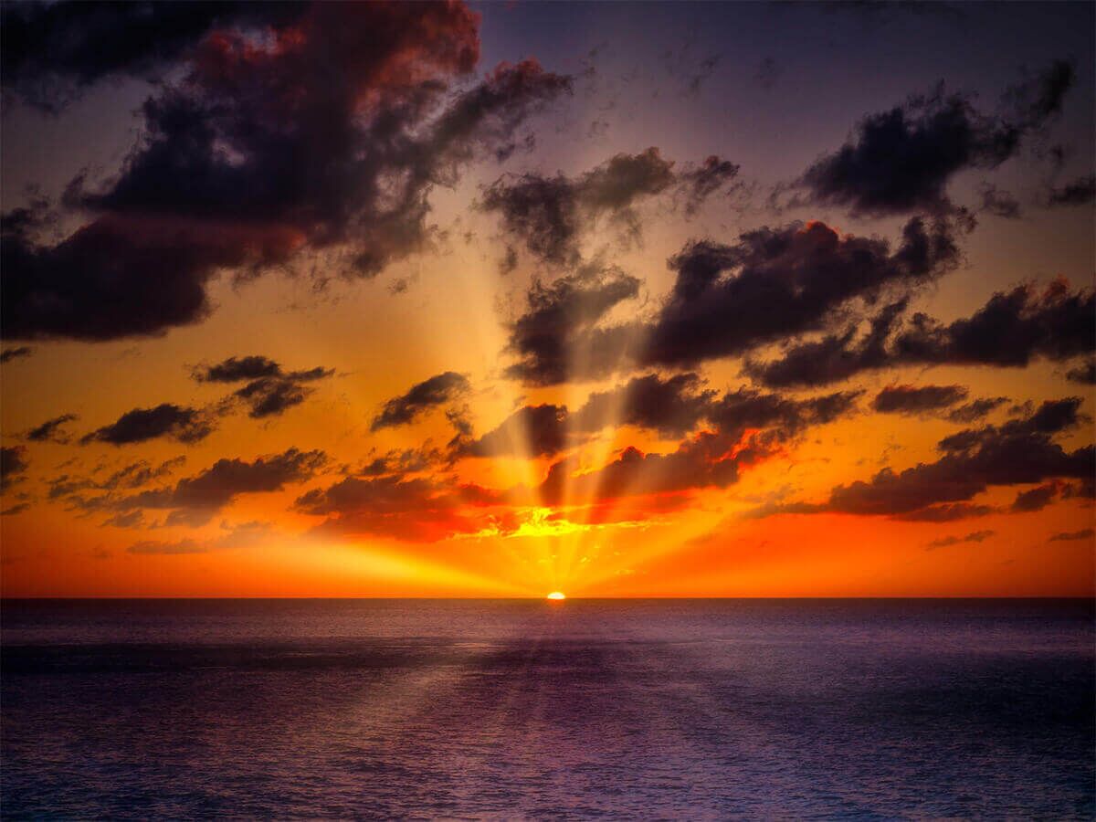 Un coucher de soleil sur l’océan, avec des nuages.