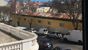 Une vue d’un parking avec plusieurs voitures et, au fond, un bâtiment à la façade jaune.