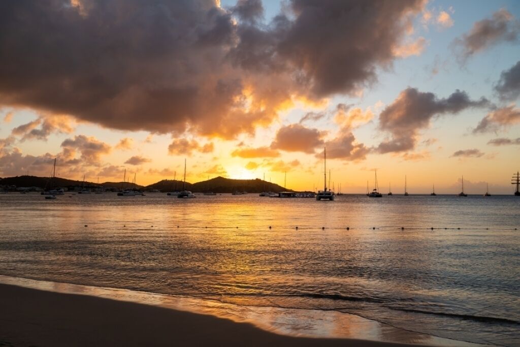Une plage avec des bateaux et un coucher de soleil.