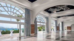 Un interior espacioso con ventanas amplias, techo alto y vista al mar.