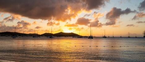 Una playa con barcos y una puesta de sol.