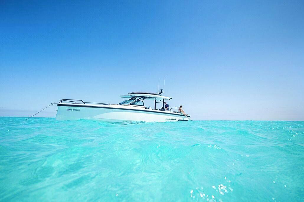 A boat with a name and registration number on its side, floating on clear turquoise water.