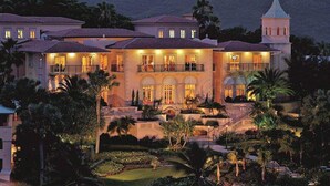 A large, multi-story building with a prominent tower, surrounded by lush landscaping and palm trees. - Ritz-Carlton Club® / 2 Bed Lux Suite* (Fri to Fri) (East End)