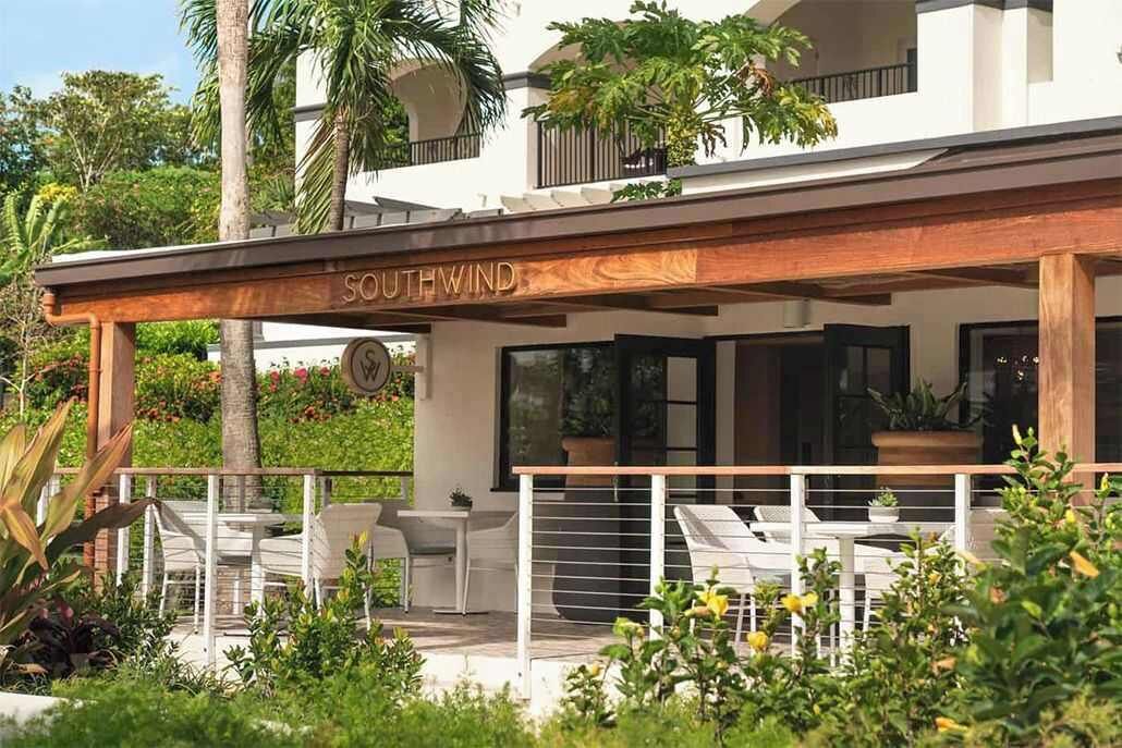 Um edifício moderno com área de estar coberta ao ar livre, uma placa com a inscrição 