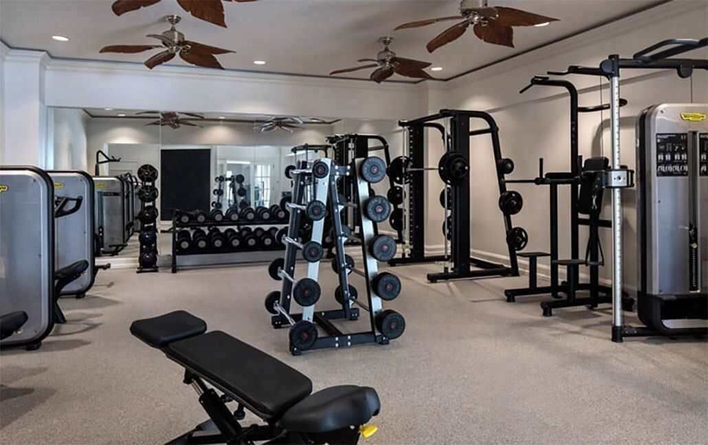 A gym with various weightlifting equipment, a bench, and dumbbells.