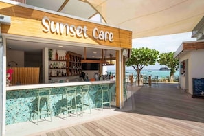A bar named 'Sunset Care' with a view of the sea.