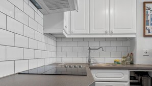 A kitchen with white cabinets, a stainless steel sink, and a built-in stove. - Pass the Keys |Bright Town-Centre Flat with Outdoor Area (Ulverston)