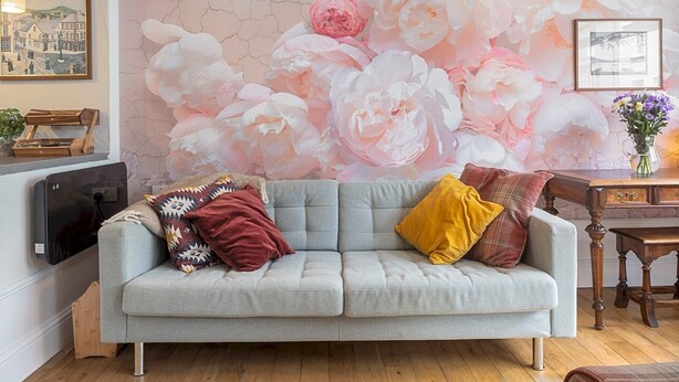 A living room with a grey sofa, a wooden coffee table, and a floral mural on the wall. - Pass the Keys |Bright Town-Centre Flat with Outdoor Area (Ulverston)