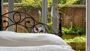 A bed with a metal headboard and a view of a garden through a window. - Pass the Keys |Bright Town-Centre Flat with Outdoor Area (Ulverston)