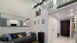 A modern living room with a grey sofa, a large mirror, and a wooden floor.