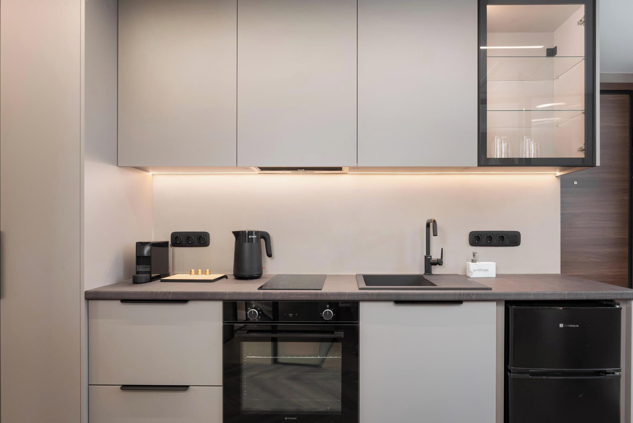 A modern kitchen with a built-in oven, a coffee maker, and a sink.