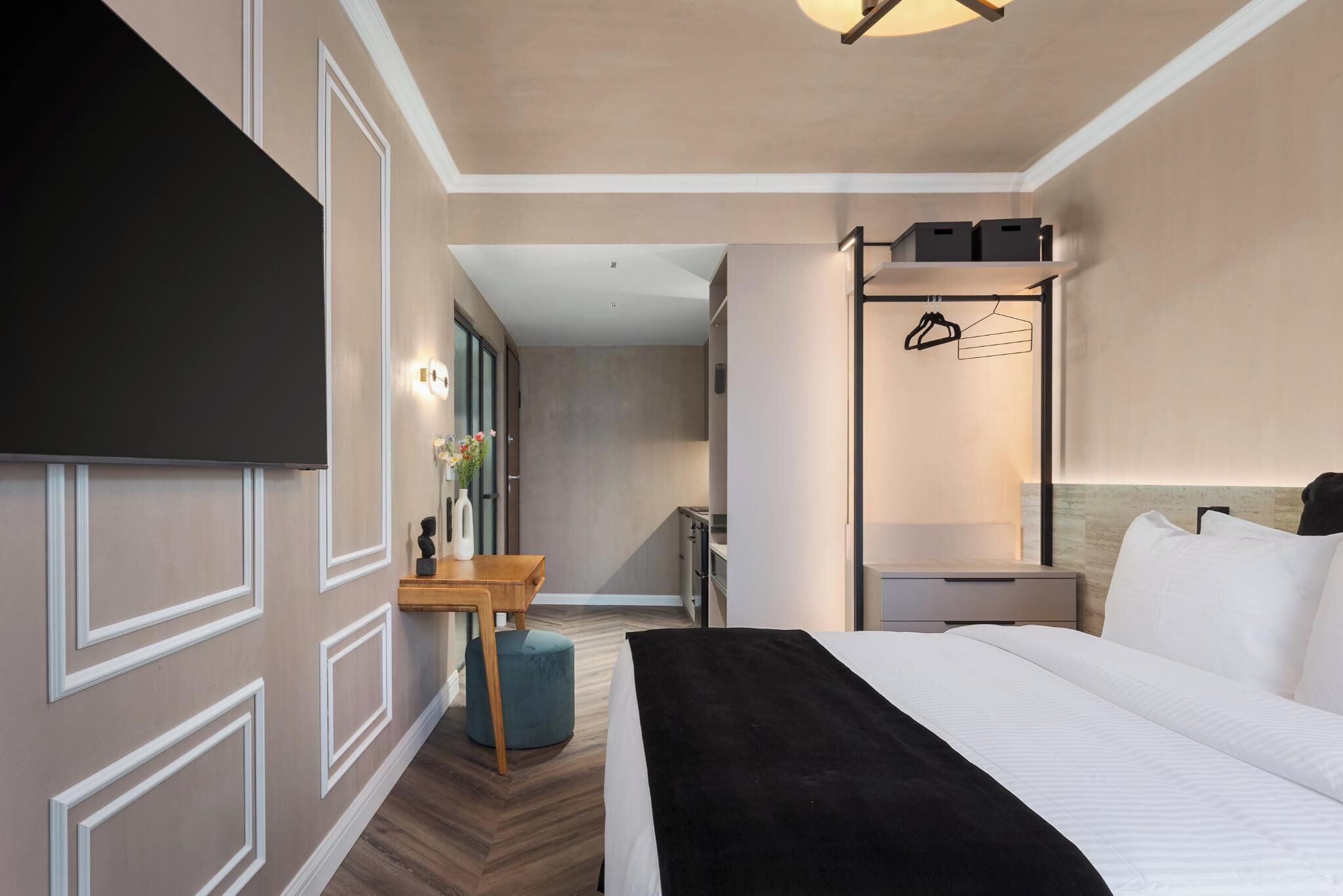 A hotel room with a bed, a desk, a chair, a wardrobe, and a mirror.
