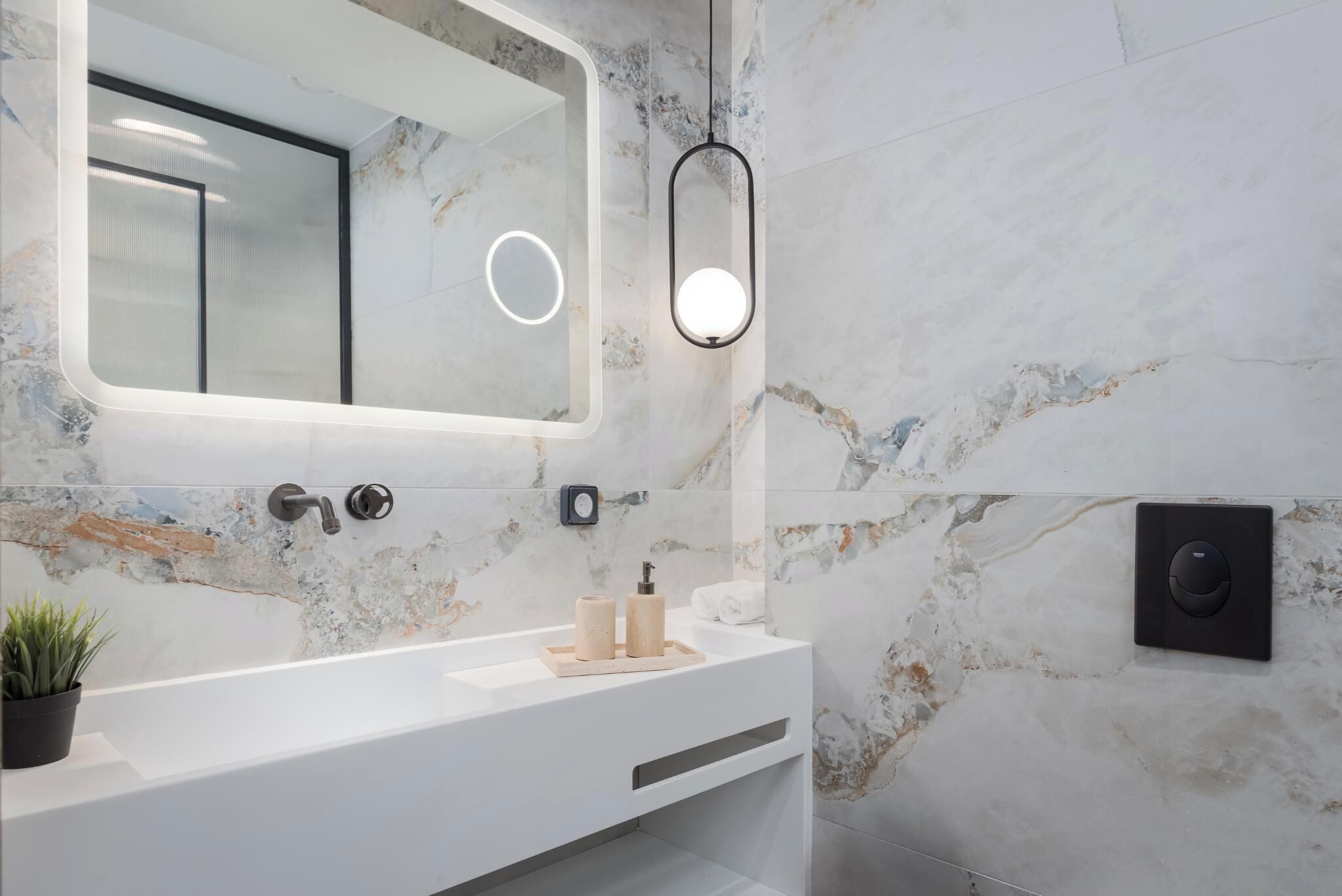 A modern bathroom with a white vanity, a large mirror, and a marble backsplash.
