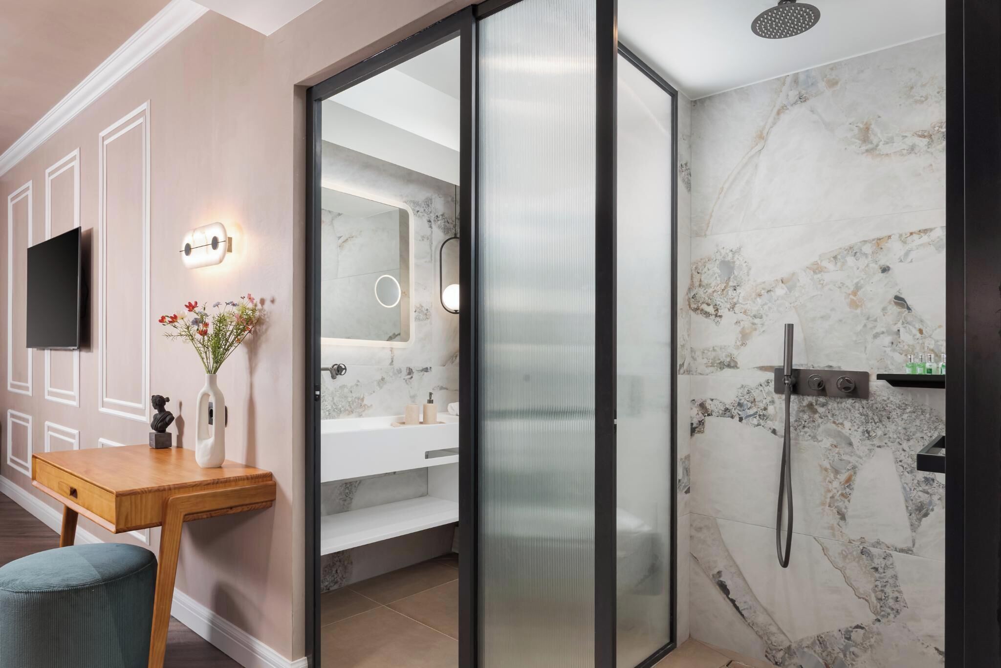 Un bagno moderno con cabina doccia in vetro, pareti in marmo e un mobile lavabo con specchio.