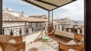 A balcony with wicker furniture, a small table, and a glass of wine. - Room 'Federico 2°' with Mountain View, Wi-Fi and Air Conditioning (Giuliana)