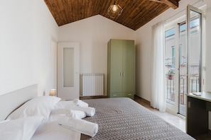 Een slaapkamer met een bed, een groene garderobe, een radiator en een balkon met uitzicht.