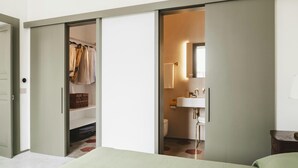 A bedroom with a bed, a closet with hanging clothes, and a bathroom with a sink and toilet. - La Canonica Suites (Cannole)