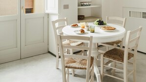 A dining area with a round table, white chairs, and a view through an open door. - La Canonica Suites (Cannole)
