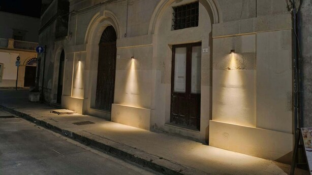 A building with arched doorways and illuminated walls, suggesting a historical or traditional architecture. - La Canonica Suites (Cannole)