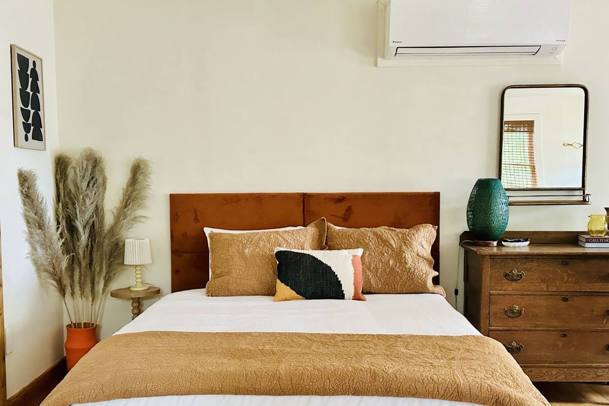 A neatly made bed with a brown headboard, a bedside lamp, and decorative pillows.
