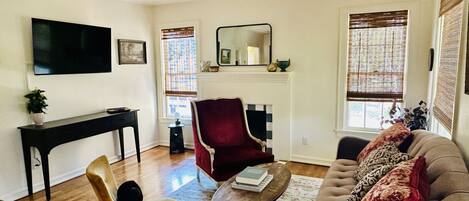 Una sala de estar con televisión, chimenea, un sillón rojo, sofá y ventilador de techo.