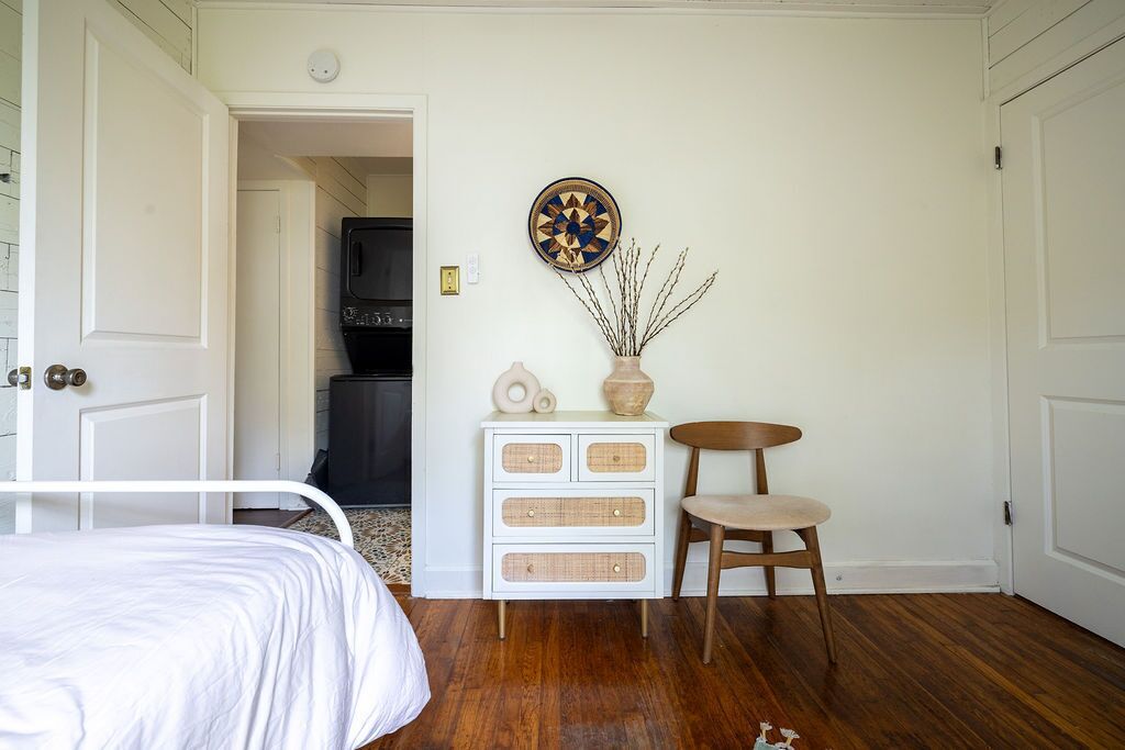 A bedroom with a bed, a dresser, a chair, and a wall-mounted clock.