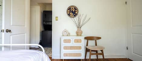 A bedroom with a bed, a dresser, a chair, and a wall-mounted clock.