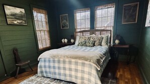 Een slaapkamer met een groot bed, een houten stoel en een vloerkleed.