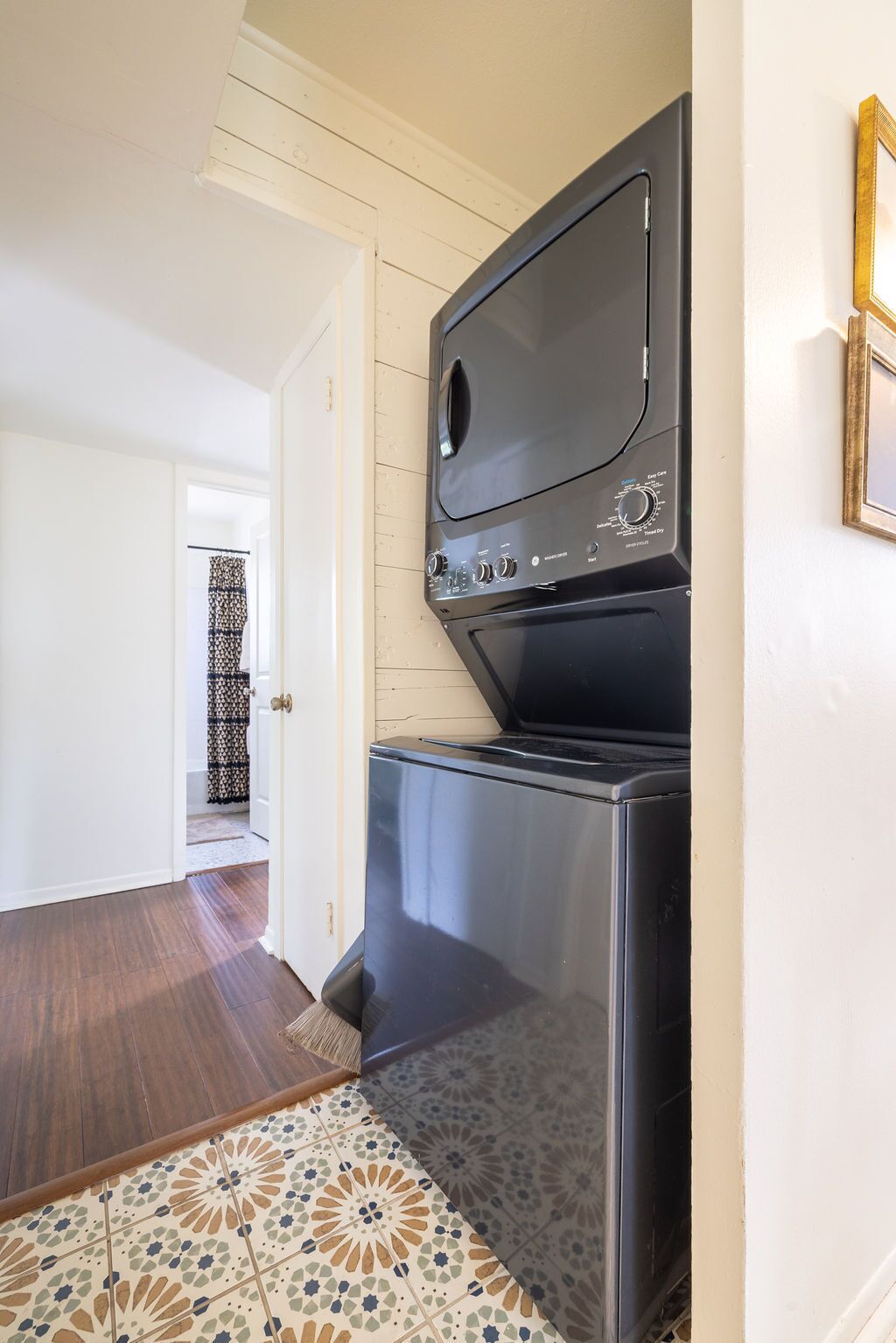 A compact kitchen with a built-in oven and microwave, a patterned tile floor, and a door leading to another room.