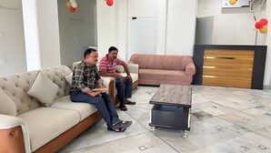 Ein modernes Wohnzimmer mit einem beigen Sofa, einem rosafarbenen Sofa und einem Boden mit Marmorfliesen.