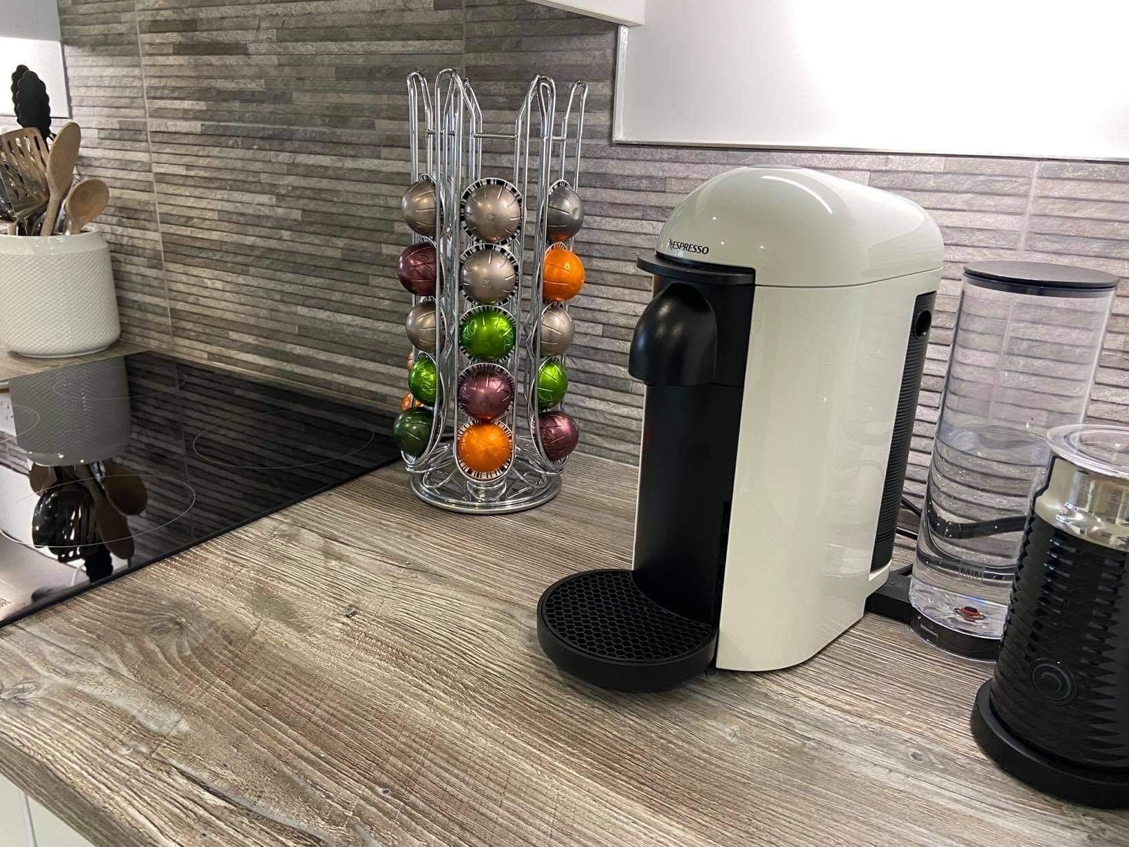 A kitchen with a coffee maker, a fruit ball holder, and a coffee grinder.