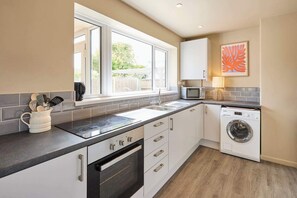 A modern kitchen with a built-in oven, microwave, and washing machine. - Host Stay The Beach House (Cromer)