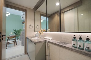 A modern bathroom with a large mirror, a vanity with a sink, and toiletries.