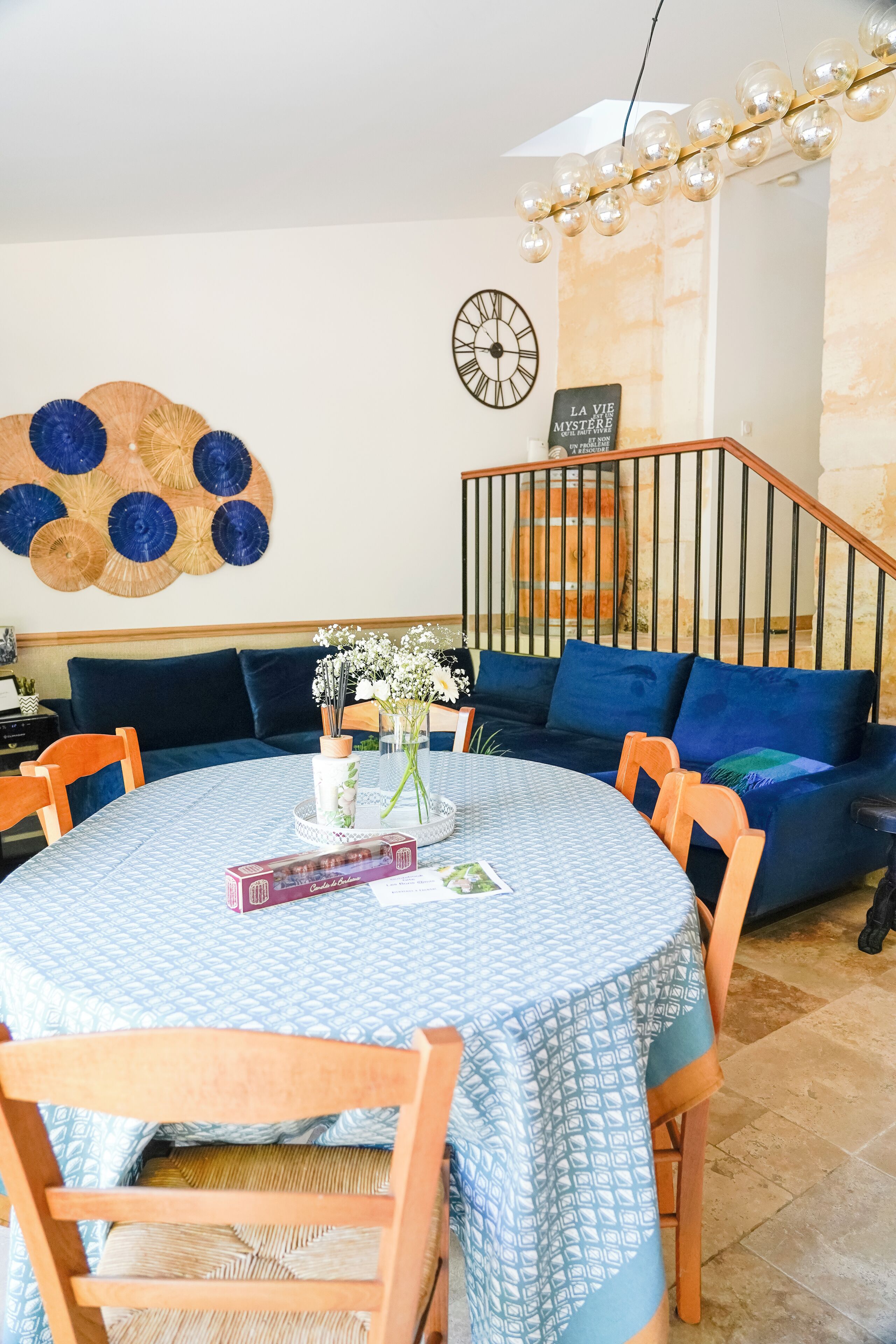 Un coin repas comprenant une table ronde, des chaises, une horloge et un élément de décoration murale.