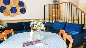 A dining area with a round table, chairs, a clock, and a wall decoration.