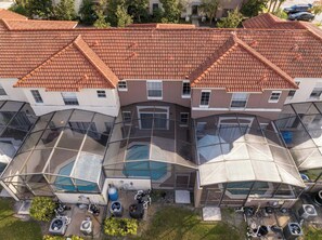 Un immeuble à plusieurs étages, doté d’un toit recouvert de tuiles rouges, de grandes fenêtres en verre et d’une piscine.