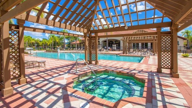 Un área de piscina techada con jacuzzi, sillas de descanso y vistas a un edificio de resort.