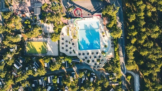 An aerial view of a residential area with a central swimming pool, surrounded by houses and greenery. - ZEcamping 4 étoiles familial 1km plage espace aquatique mobil-home 36m2 (Les Mathes)