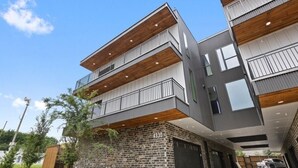 A modern multi-story building with a brick facade, balconies, and a garage. - The Eastwood Escape (Dallas)