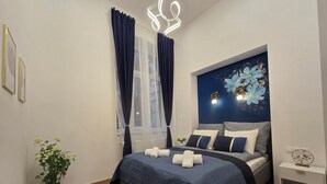 Une chambre à coucher moderne, avec un lit, des tables de chevet, une plante en pot et un élément décoratif mural.