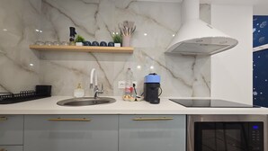 Une cuisine moderne dotée d’un pare-feu en marbre, d’appareils électroménagers en acier inoxydable et d’un four à micro-ondes encastré.