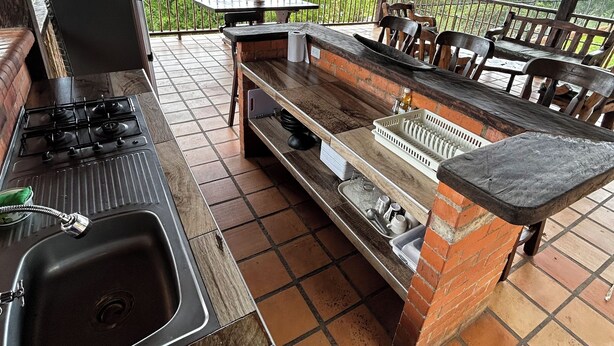 An outdoor kitchen with a gas stove, sink, and bar area, overlooking a scenic landscape. - 5BR Cabin w/Heated Pool+Mountain Views/Fire Place (Villahermosa)