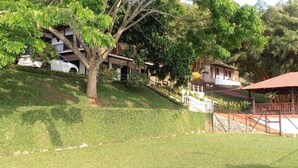 A hillside property with multiple buildings, including a large house with a balcony and a smaller structure with a red roof. - 5BR Cabin w/Heated Pool+Mountain Views/Fire Place (Villahermosa)