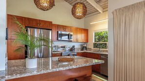 A modern kitchen with wooden cabinets, stainless steel appliances, a granite countertop, and a large island with seating.