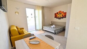 Una camera d'albergo con un letto, un divano, un tavolo da pranzo e una televisione.