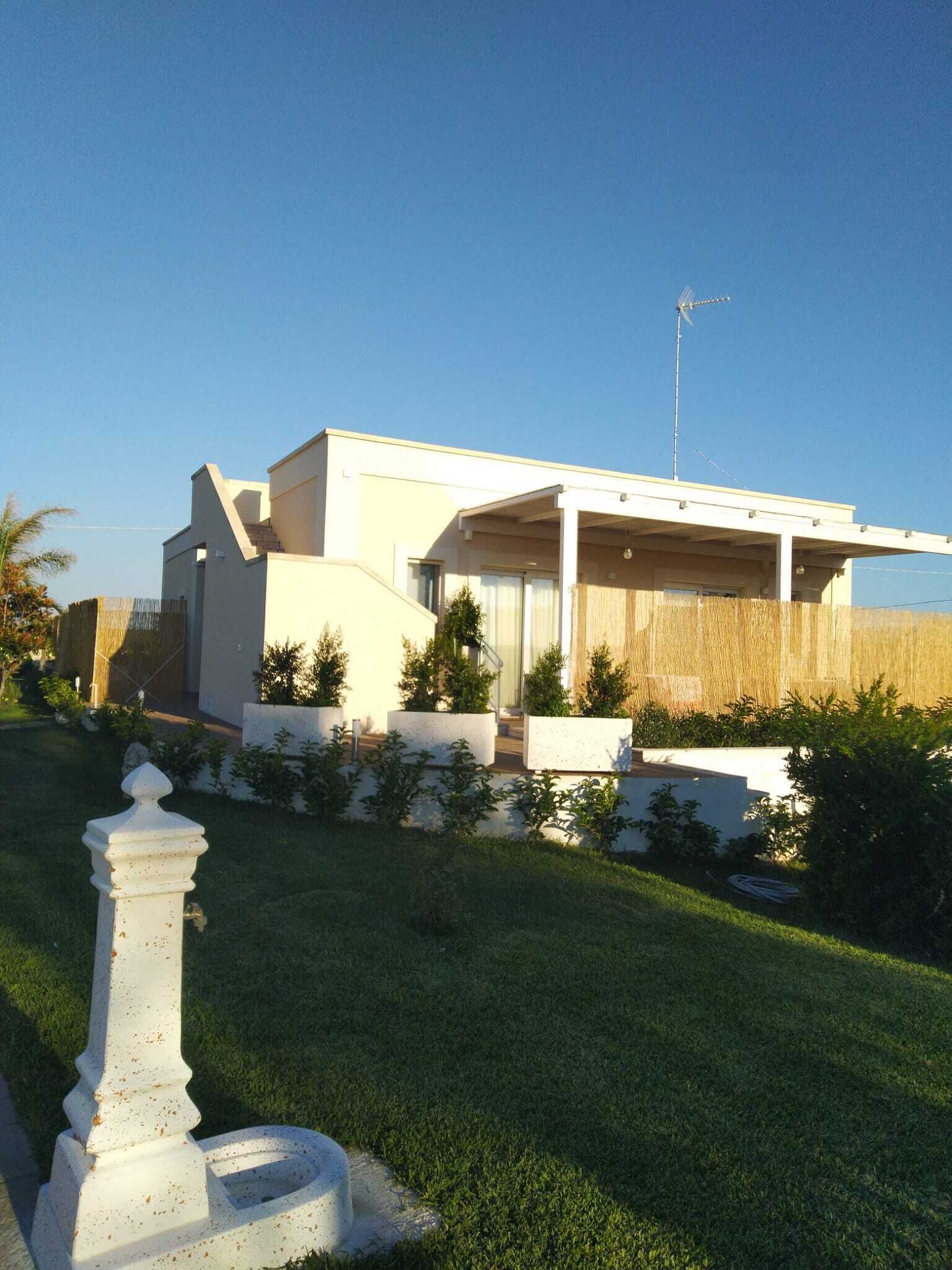 A modern two-story house with a flat roof, a large front porch, and a satellite dish.