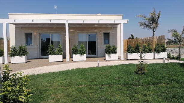 Una moderna casa a due piani con un portico coperto, ampie finestre e un prato ben curato.