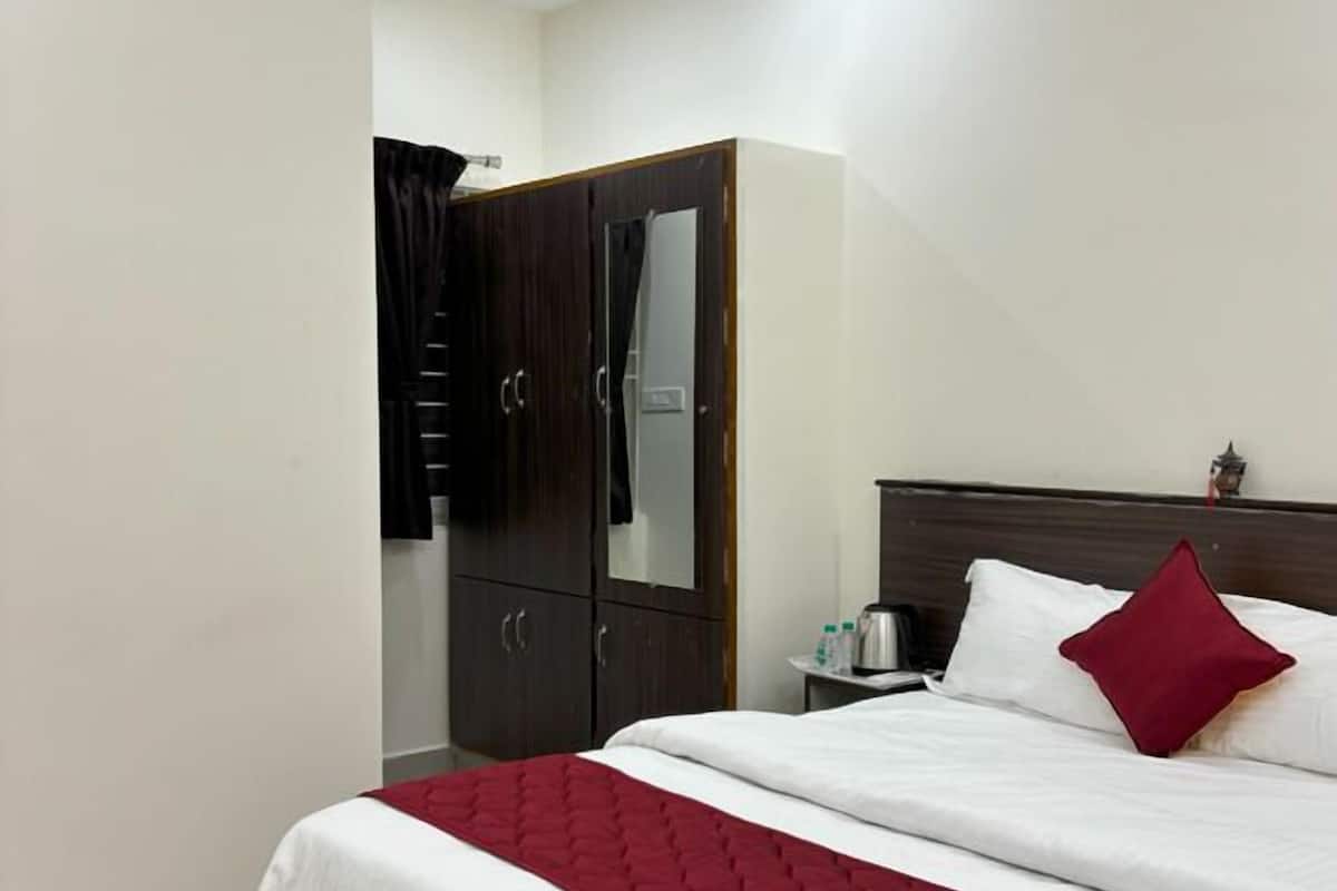 A hotel room with a bed, a wardrobe, a ceiling fan, and a nightstand with a lamp.