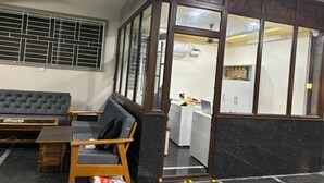 A lobby with a sofa, a wooden table, and a reception desk. - PS ELITE HOME STAY (Tirupati)