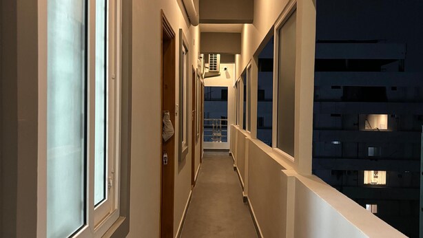 A narrow corridor with large windows on both sides, leading to a door at the end. - PS ELITE HOME STAY (Tirupati)